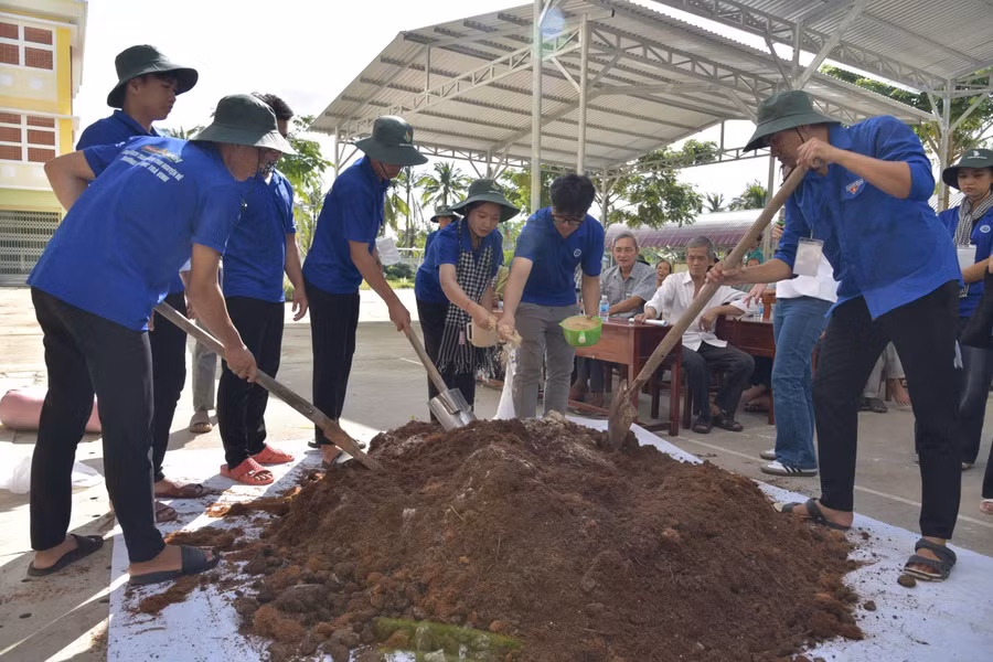 Sinh viên Trường Đại học Trà Vinh hướng dẫn bà con làm phân hữu cơ. Ảnh: Bình An