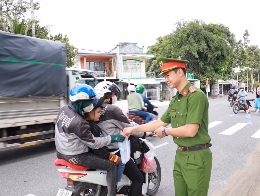 Cán bộ, chiến sĩ Công an phát nước suối và khăn lạnh cho người dân về quê nghỉ lễ.