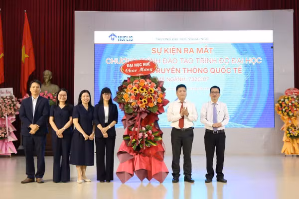 Lãnh đạo Đại học Huế (phải) tặng hoa chúc mừng lãnh đạo Trường Đại học Ngoại ngữ, Đại học Huế (bên trái) tại buổi lễ.