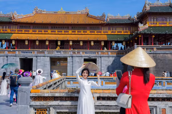 Người dân, du khách mặc áo dài, đội nón lá Huế chụp hình trước Đại Nội ngày lễ Quốc khánh 2026. (Ảnh: Đình Hoàng)