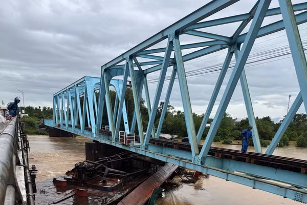 Xà lan bị nước lũ cuốn trôi, mắc kẹt vào cầu đường sắt.