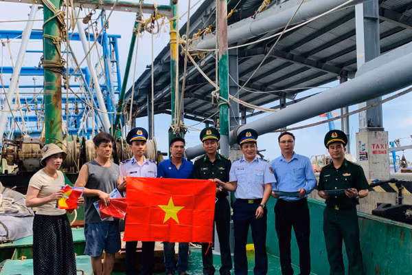 Lực lượng chức năng tuyên truyền lưu động và tặng cờ Tổ quốc cho ngư dân.