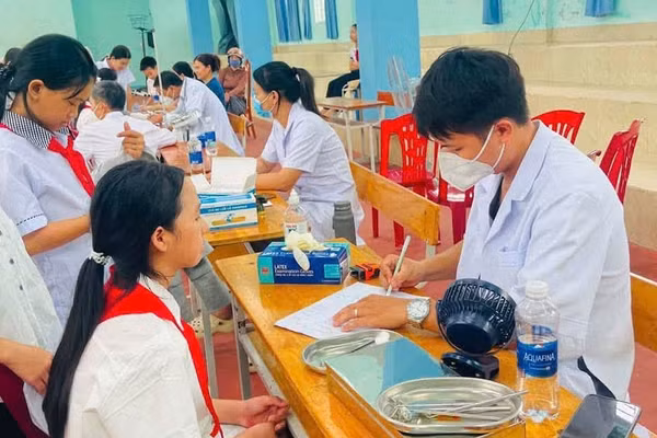 Cán bộ y tế cơ sở khám sức khoẻ cho học sinh.