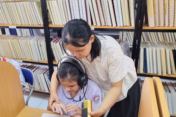 Cô giáo hướng dẫn cho học sinh tại thư viện của Trường PTĐB Nguyễn Đình Chiểu.