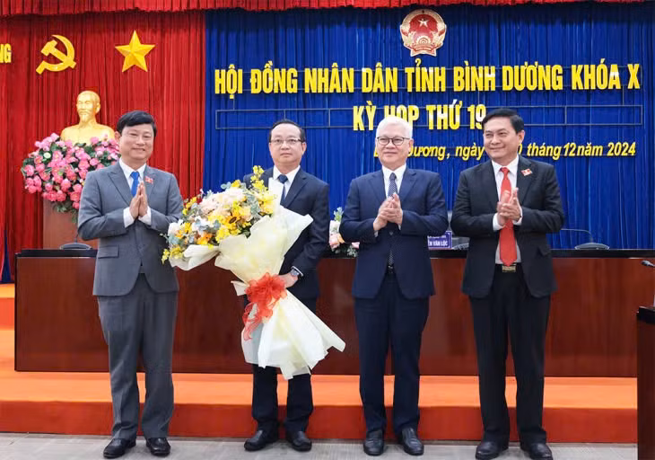 Ông Bùi Minh Thạnh (thứ 2 từ trái qua) nhận hoa chúc mừng từ lãnh đạo tỉnh Bình Dương. (Ảnh: Phương Chi)