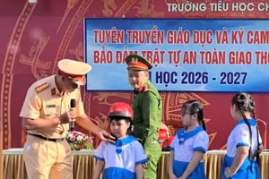 Cán bộ Phòng CSGT, Công an tỉnh An Giang hướng dẫn học sinh đội mũ bảo hiểm đúng quy định.