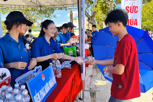 Thanh niên tình nguyện phát nước miễn phí tại điểm thi Trường THPT Đặng Thai Mai (Nghệ An).