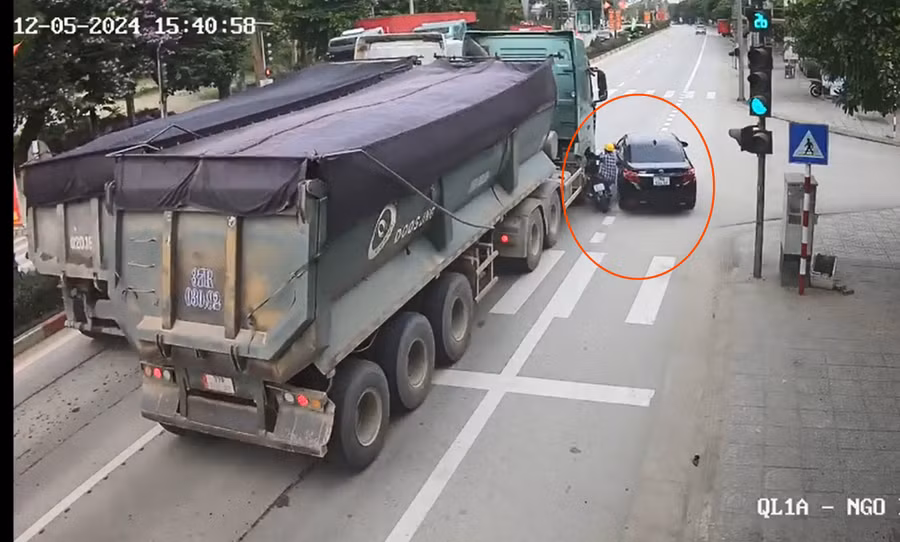 Do vượt ẩu, ô tô đã hất người phụ nữ đi xe máy vào xe tải. (Ảnh cắt từ clip) Do vượt ẩu, ô tô đã hất người phụ nữ đi xe máy vào xe tải. (Ảnh cắt từ clip)