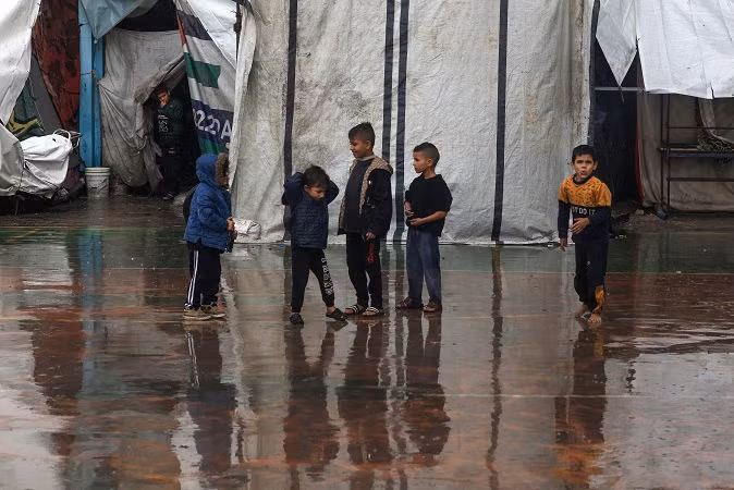 Trẻ em Palestine đứng ngoài trời mưa tại một trại dành cho người di dời Trẻ em Palestine đứng ngoài trời mưa tại một trại dành cho người di dời