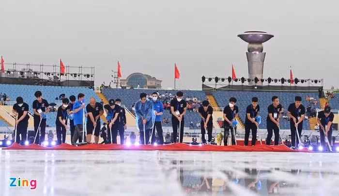 Sau cơn mưa lớn chiều nay, sân khấu khai mạc SEA games 31 đã bị ngập nước. Hàng trăm tình nguyện viên tích cực lau dọn mặt sân khấu chính trước giờ khai mạc. Ảnh: Việt Linh.