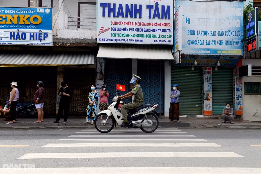 Một cán bộ Quận Bình Thạnh chạy xe phát loa nhắc nhở người dân xếp hàng mua sắm thực hiện việc giãn cách để đảm bảo an toàn mùa dịch. Nguồn: Dân Trí.