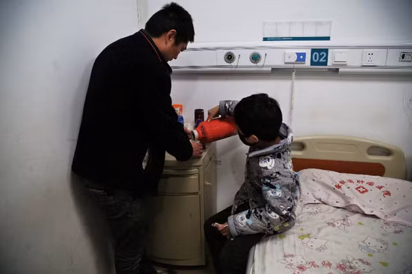 Chen Minghao helps his father serve tea for his visitors, who came to see them at the hospital