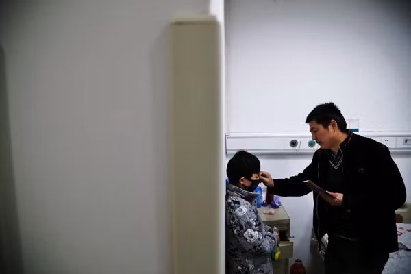 Chen Yuntao helps his son wear a mask at the hospital