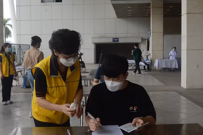 Người nước ngoài thực hiện khai thông tin trên phiếu sàng lọc tiêm chủng. Nguồn: SYT Hà Nội.