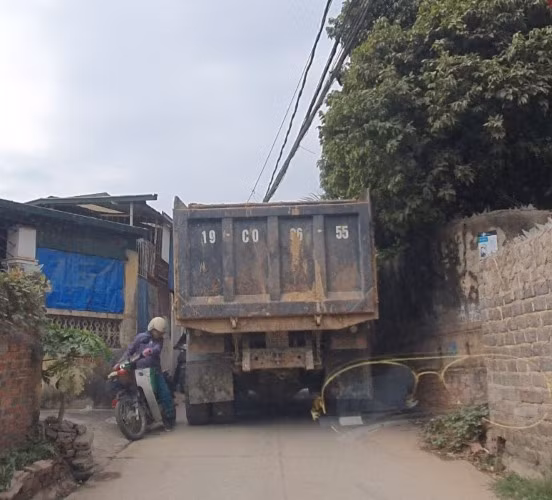 Xe tải trọng nặng chở đất qua khu dân cư chật hẹp.
