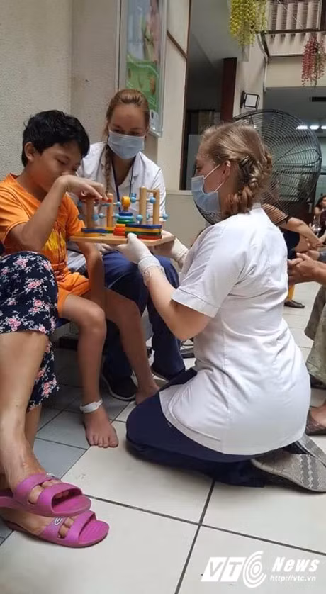 Nu sinh Dan Mach xinh dep quy xuong nang niu benh nhan nhi o Bach Mai - Anh 1