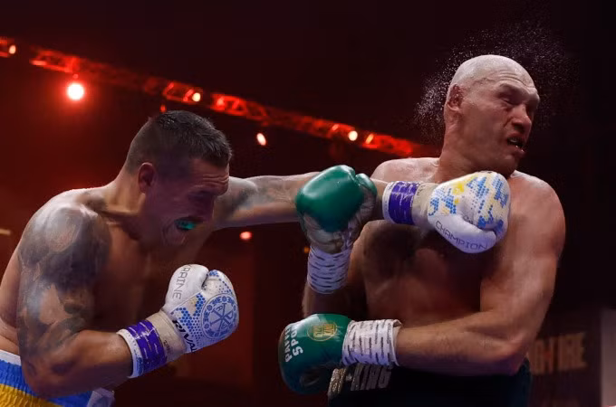 Tyson Fury lĩnh cú đấm vào mặt từ đối thủ Oleksandr Usyk trong trận thống nhất bốn đai quyền Anh hạng nặng tại Riyadh tối 18/5. Ảnh: Reuters.