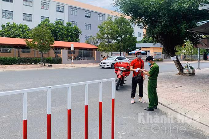Công an xã Vinh Ngọc kiểm tra giấy tờ đi đường của một shipper đến giao hàng tại khu đô thị Vĩnh Điềm Trung, Nha Trang. Ảnh: Báo Khánh Hòa.