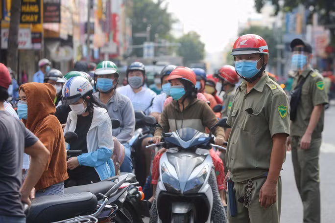 Nhiều người dân ở các quận lận cận dù không có phiếu đi chợ tại đây nhưng vẫn bất chấp đứng đợi phía bên ngoài cổng để có thể được vào, lực lượng chức năng phải có mặt để điều phối. Nguồn: NLĐ.