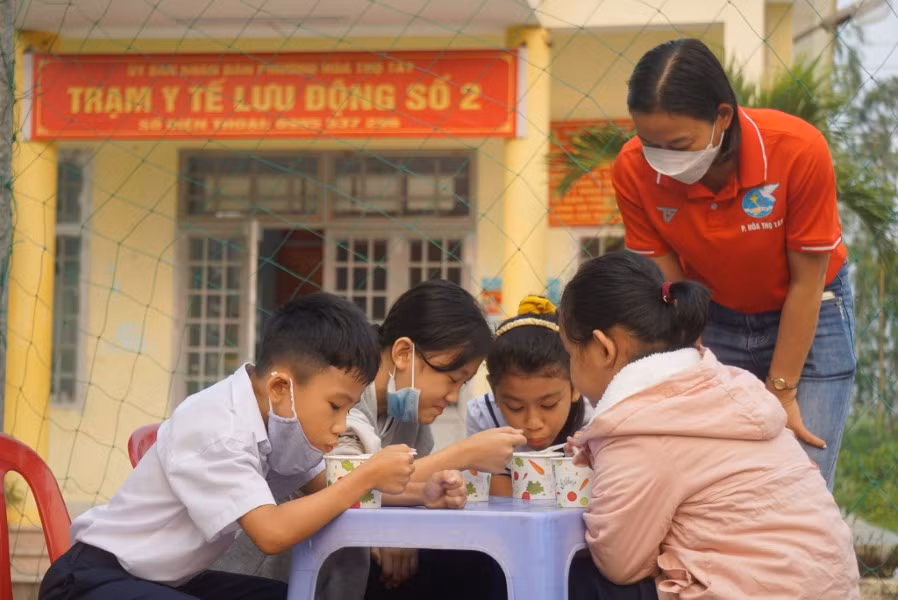 Những em học sinh thưởng thức những món ăn do chi hội phụ nữ nấu.