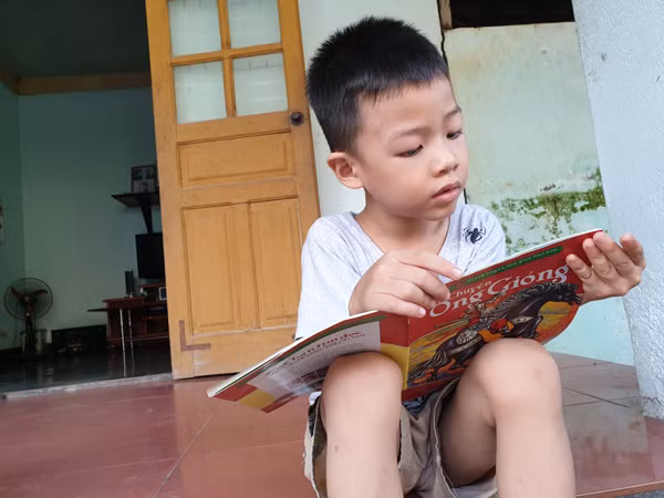 Chưa học chữ nhưng Lộc đọc sách, đọc truyện vanh vách. Ảnh: T.G.