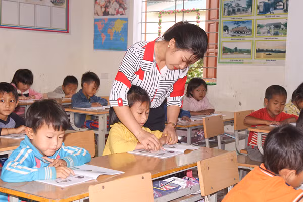 Cô giáo hướng dẫn học sinh học bài trên lớp