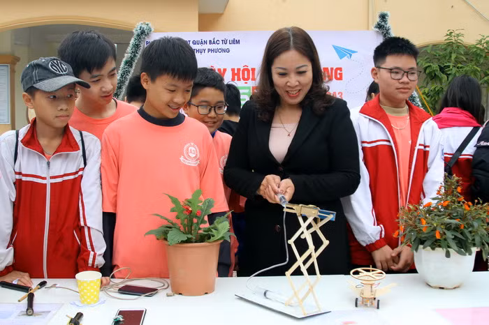 Nhà giáo Hoàng Ngọc Lan trải nghiệm mô hình cần trục nâng thủy lực được học sinh lớp 7 chế tạo từ những vật liệu dễ kiếm.