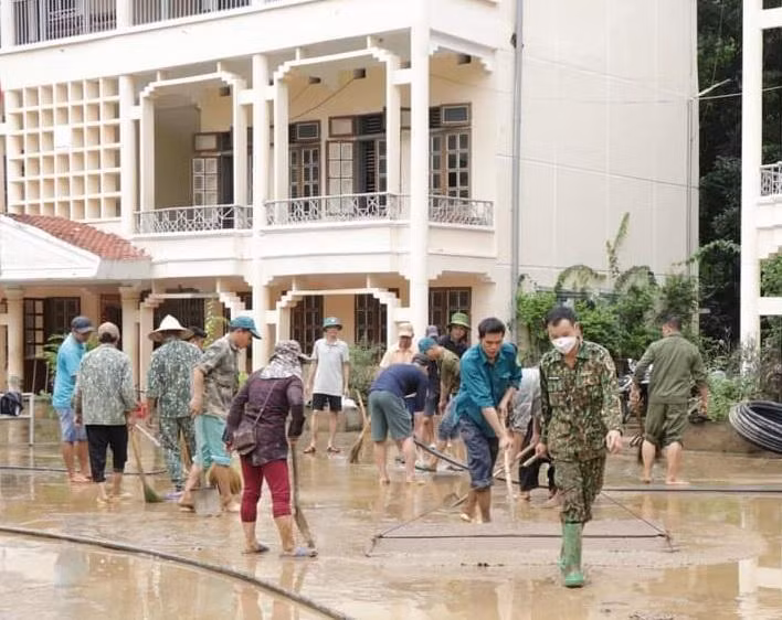 Phụ huynh và lực lượng chức năng cùng giáo viên nhà trường THCS Tạ Khoa dọn dẹp bùn đất sau mưa lũ.