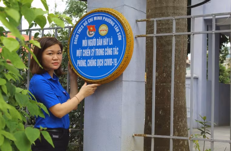 Trần Huyền Trang – Bí thư Đoàn phường Tân Sơn (TP Thanh Hóa) bên khẩu hiệu phòng chống dịch bệnh Covid-19 được làm từ lốp xe.
