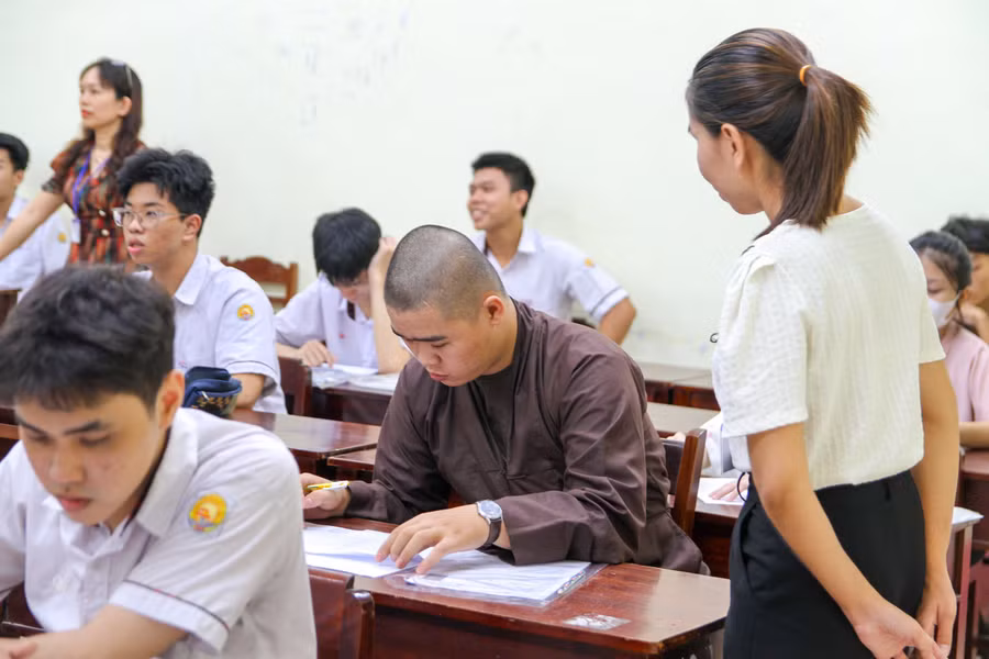 Cán bộ coi thi hướng dẫn tăng ni đối chiếu thông tin.