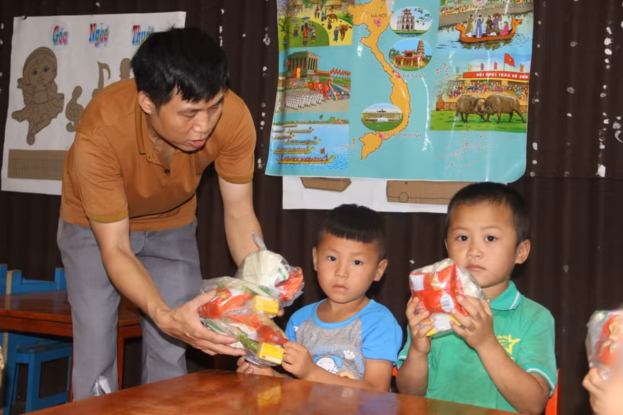Thầy Hải ân cần đưa túi bánh, kẹo cho học sinh của mình.