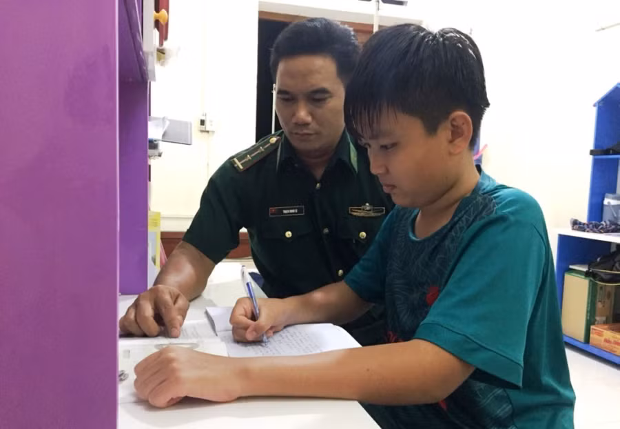 Từ khi về sống tại Đồn Biên phòng Mỹ Long, Duy luôn được những người bố nuôi kèm cặp trong học tập. Ảnh: Thạch Minh Từ khi về sống tại Đồn Biên phòng Mỹ Long, Duy luôn được những người bố nuôi kèm cặp trong học tập. Ảnh: Thạch Minh