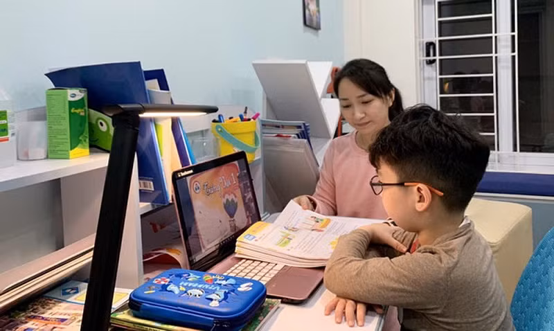 Phụ huynh hỗ trợ học sinh học trực tuyến. Ảnh: Internet