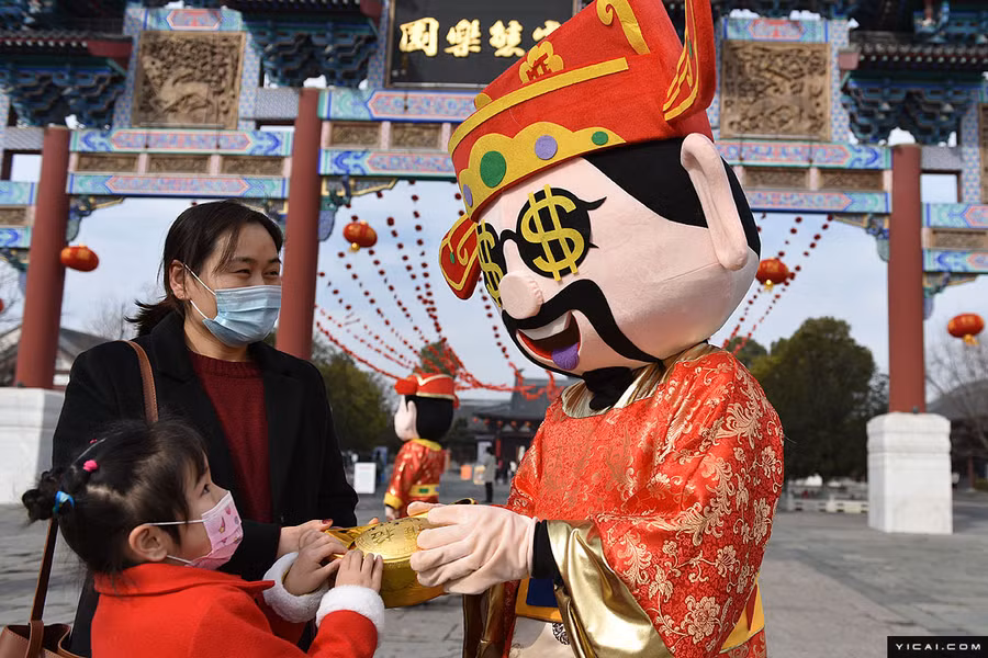 Người đàn ông này hóa trang thành Thần Tài chào đón một đứa trẻ ở tỉnh An Huy.