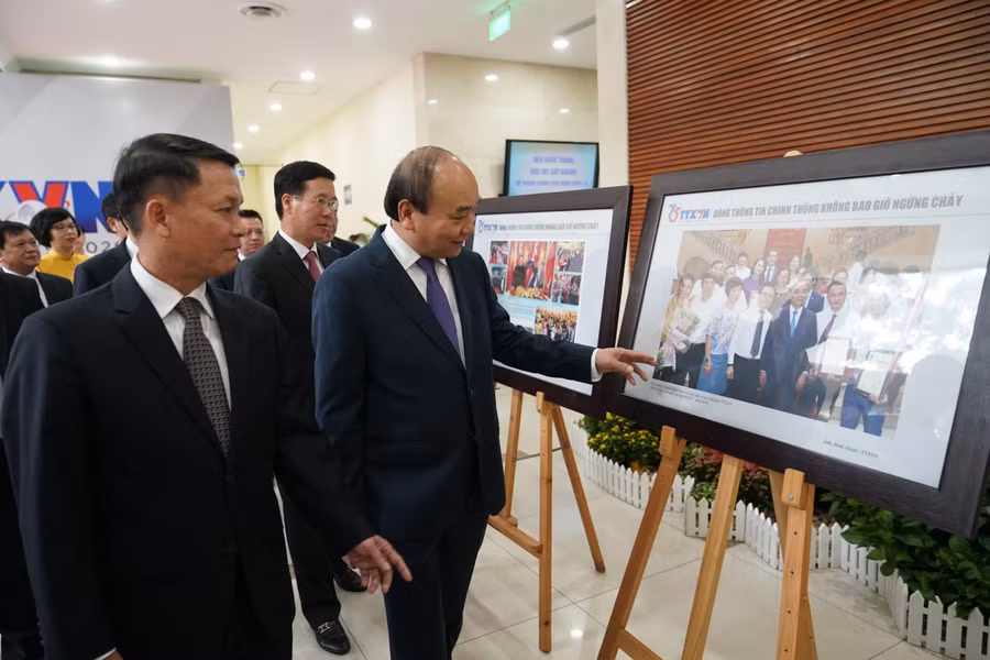 Thủ tướng Nguyễn Xuân Phúc và các đại biểu tham quan Trưng bày ảnh "75 năm TTXVN - Dòng thông tin chính thống không bao giờ ngừng chảy". - Ảnh: VGP/Quang Hiếu