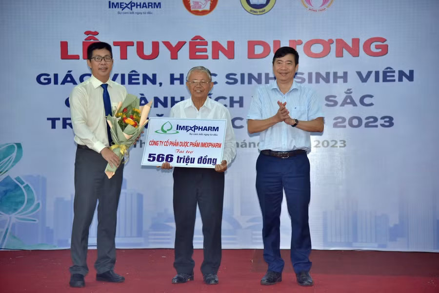 Đại diện Công ty CP Dược phẩm Imexpharm (bìa bên trái) trao bảng tượng trưng kinh phí tài trợ khen thưởng học sinh, sinh viên, giáo viên đạt thành tích xuất sắc.