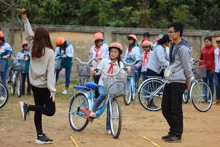 Các em học sinh được hướng dẫn cách đi xe đạp và đội mũ bảo hiểm an toàn