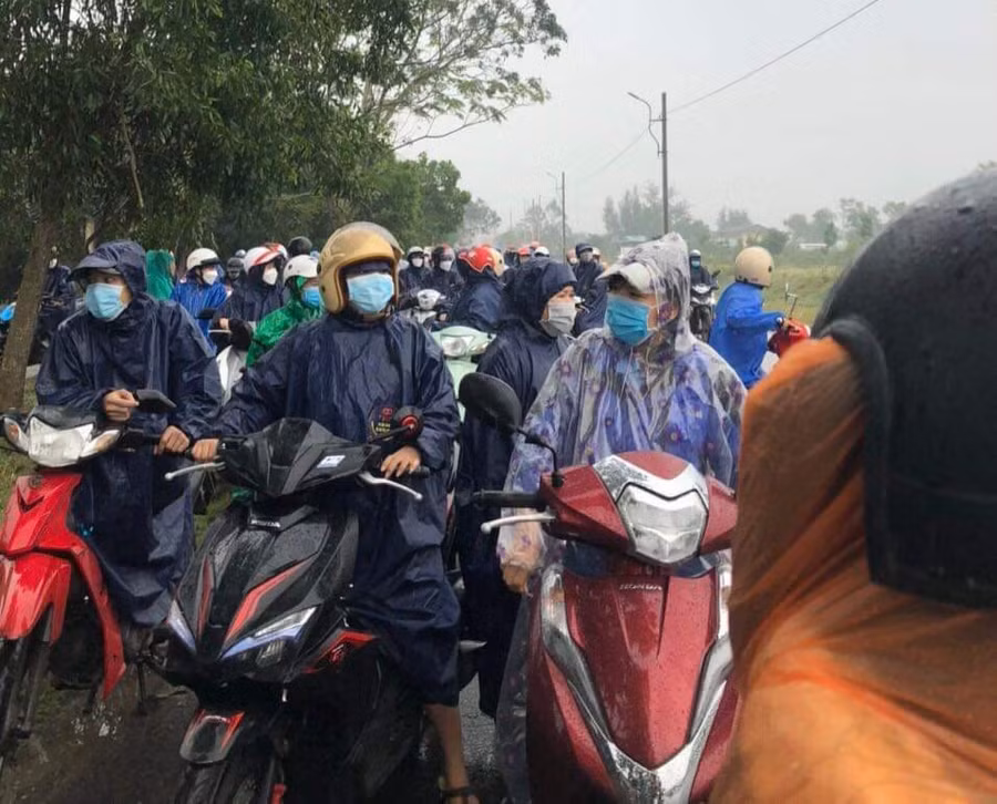 Công nhân đội mưa đứng đợi trước công ty.