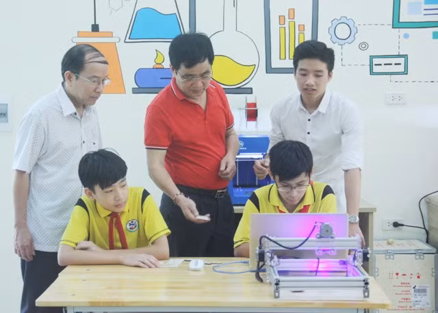 Thầy Đoàn Công Thạo (áo đỏ) - Hiệu trưởng trường THCS Giảng Võ đang cầm sản phẩm do chính học sinh của mình làm ra từ máy khắc CNC Thầy Đoàn Công Thạo (áo đỏ) - Hiệu trưởng trường THCS Giảng Võ đang cầm sản phẩm do chính học sinh của mình làm ra từ máy khắc CNC