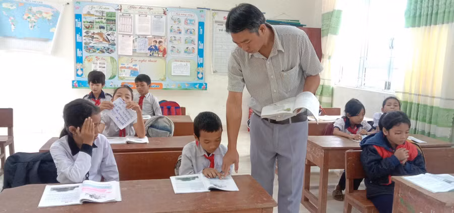 Thầy Ksơr Y Chét hướng dẫn học sinh đọc bài. Ảnh: NTCC