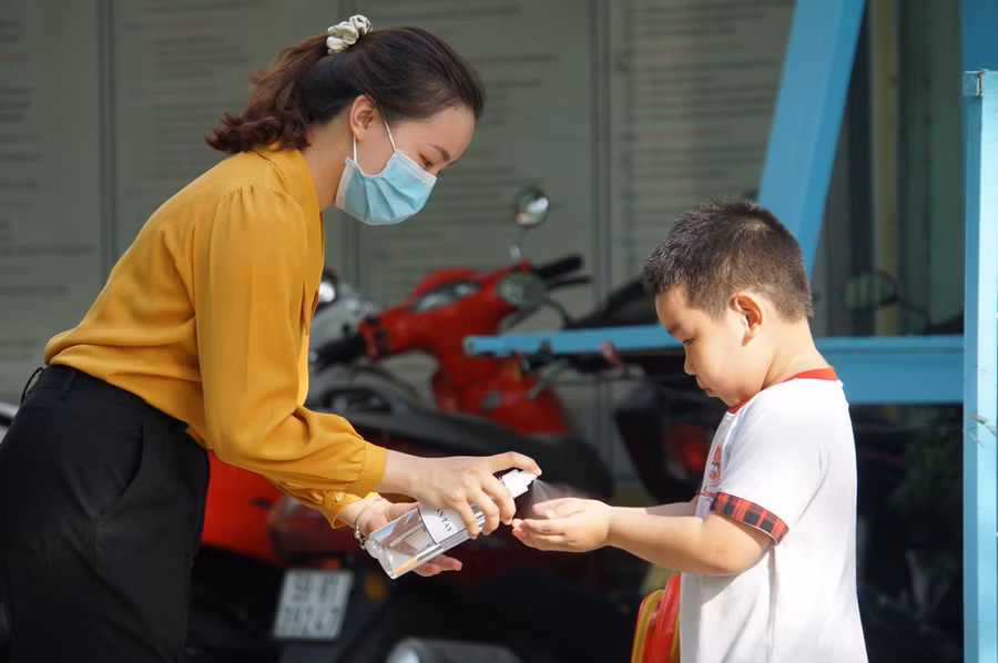 Giáo viên Trường Mầm non Hoa Phượng Đỏ (quận Gò Vấp, TPHCM) giúp trẻ rửa tay sát khuẩn trước khi vào lớp học, tháng 5/2020. Ảnh: Mạnh Tùng