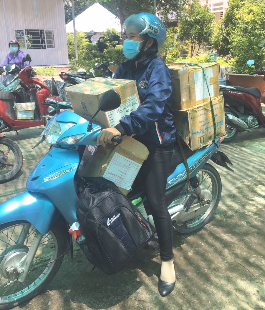 Giáo viên trên đường vận chuyển sách đến nhà cho HS.
