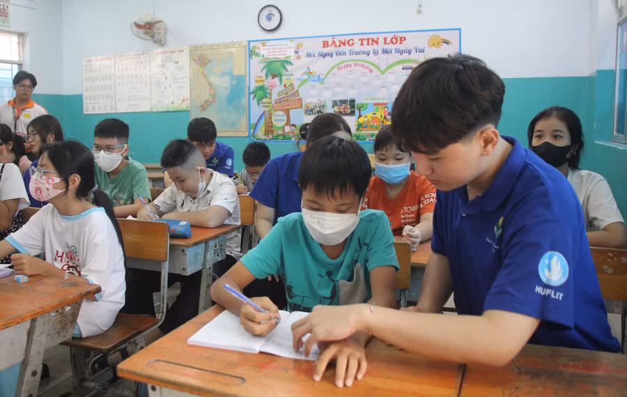 Tình nguyện viên ngồi kèm cặp cho những học sinh tiếp thu bài còn chậm.