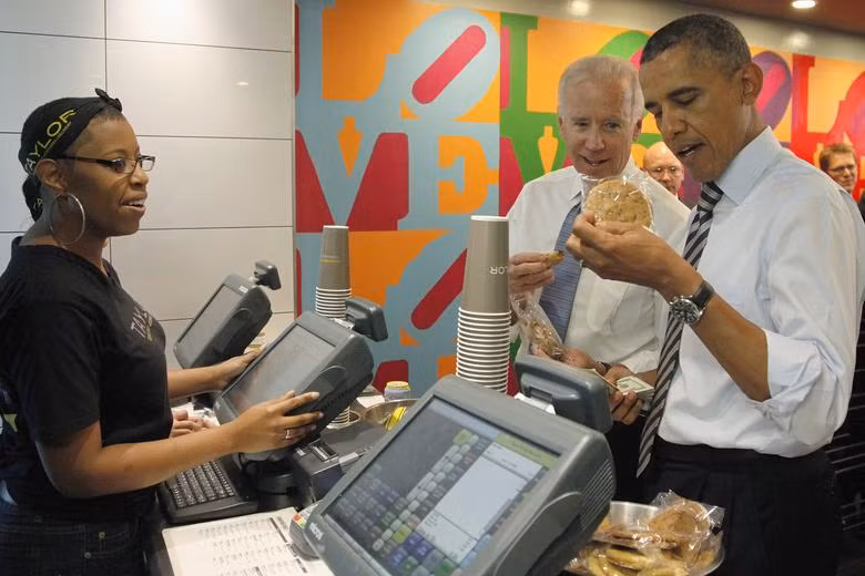 Phó Tổng thống Joe Biden giúp Tổng thống Barack Obama chọn một gói bánh quy khi họ mua bữa trưa tại một cửa hàng bánh sandwich gần Nhà Trắng ở Washington, ngày 4 tháng 10 năm 2013. REUTERS/Jonathan Ernst.