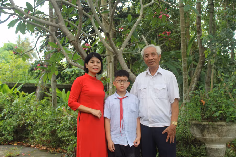 Nhà giáo Bùi Khắc Thái cùng cháu nội và con dâu Lê Thị Dung. Ảnh: Lường Toán