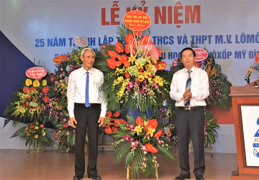 NGƯT Nguyễn Phú Cường (trái) đại diện Hệ thống giáo dục Lômônôxốp - nhận hoa chúc mừng từ ông Trần Thanh Long - Phó Chủ tịch UBND quận Nam Từ Liêm