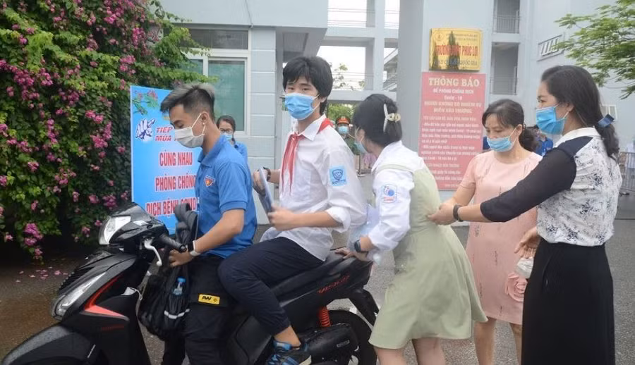 Thí sinh đến nhầm điểm thi được tình nguyện viên dùng xe máy đưa đến đúng điểm thi của mình.