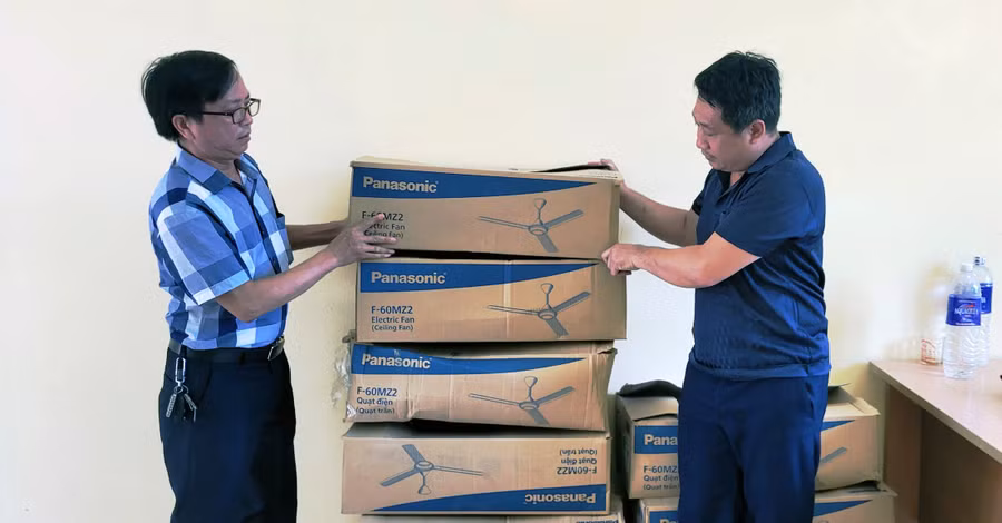 Thầy Văn (bên phải) – Hiệu trưởng Trường THCS Trung Sơn đón nhận quạt trần do Báo GD&amp;TĐ trao tặng.