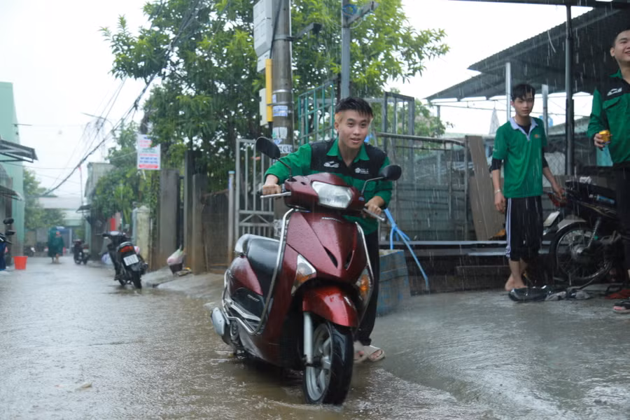 Sinh viên đội mưa dắt xe vào khu vực sửa chữa.