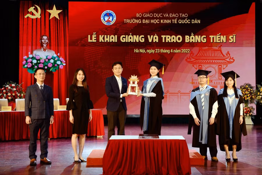 Các tân tiến sĩ trao biểu trưng của chương trình đào tạo trình độ Tiến sĩ cho nghiên cứu sinh khoá 42 tại buổi lễ.